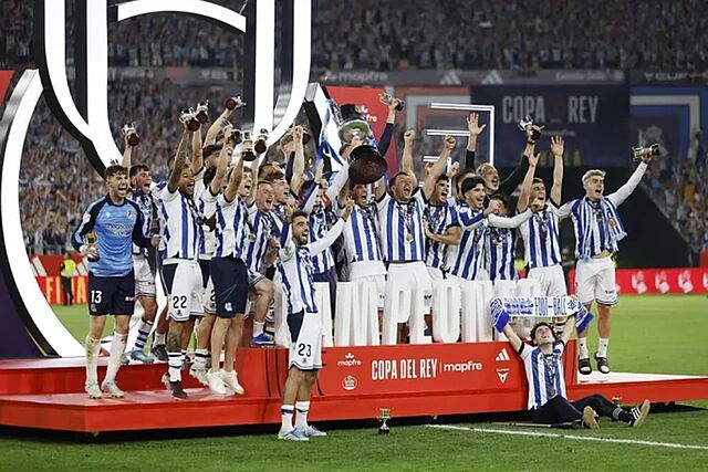 T�cnicos y futbolistas alzan el trofeo de la Copa al cielo de Sevilla.