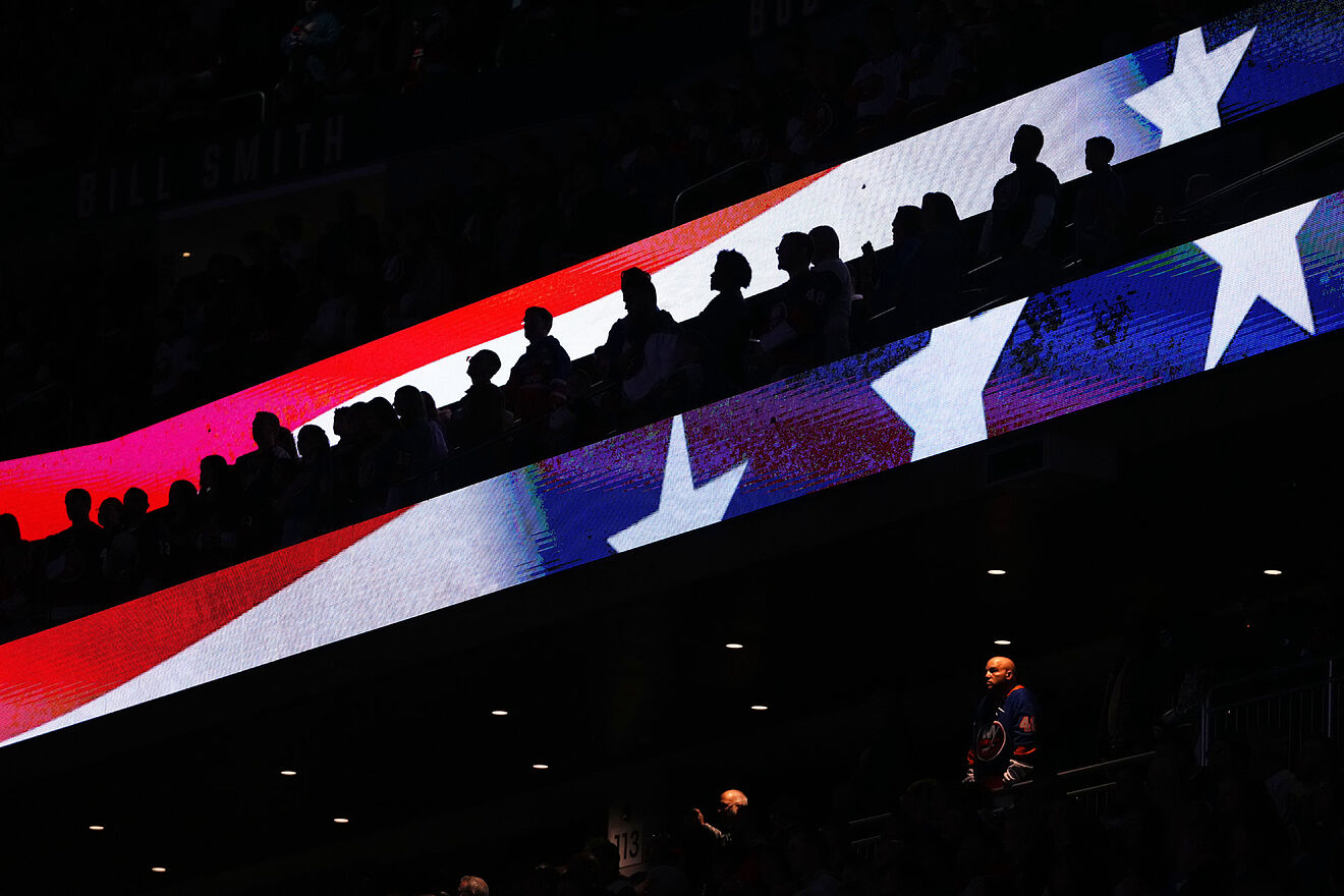 Fans stand during the playing of the national anthem at UBS Arena...