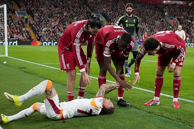 Noa Lang grimaces in pain as the Liverpool players approach.