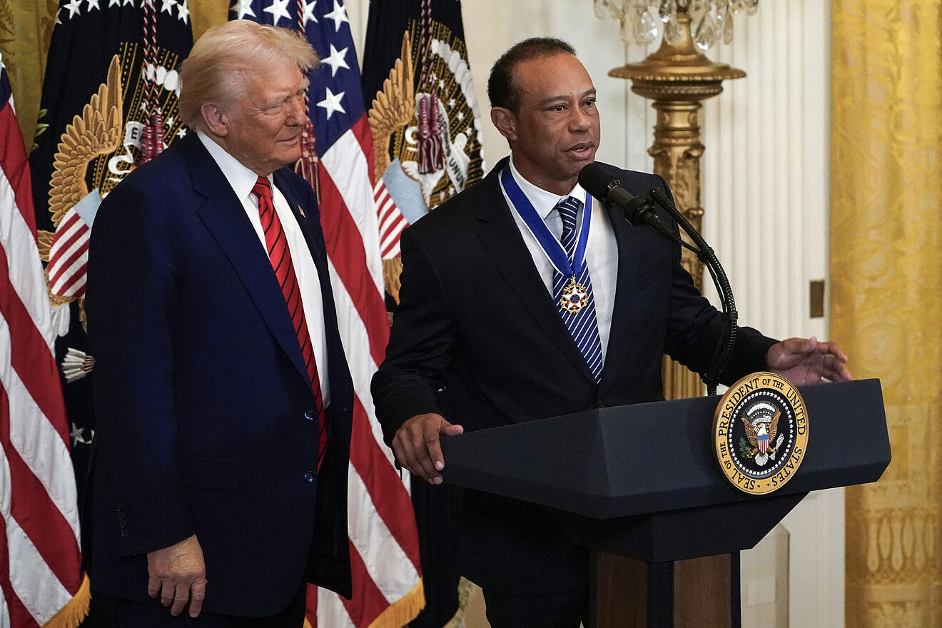 President Donald listens as Tiger Woods speaks