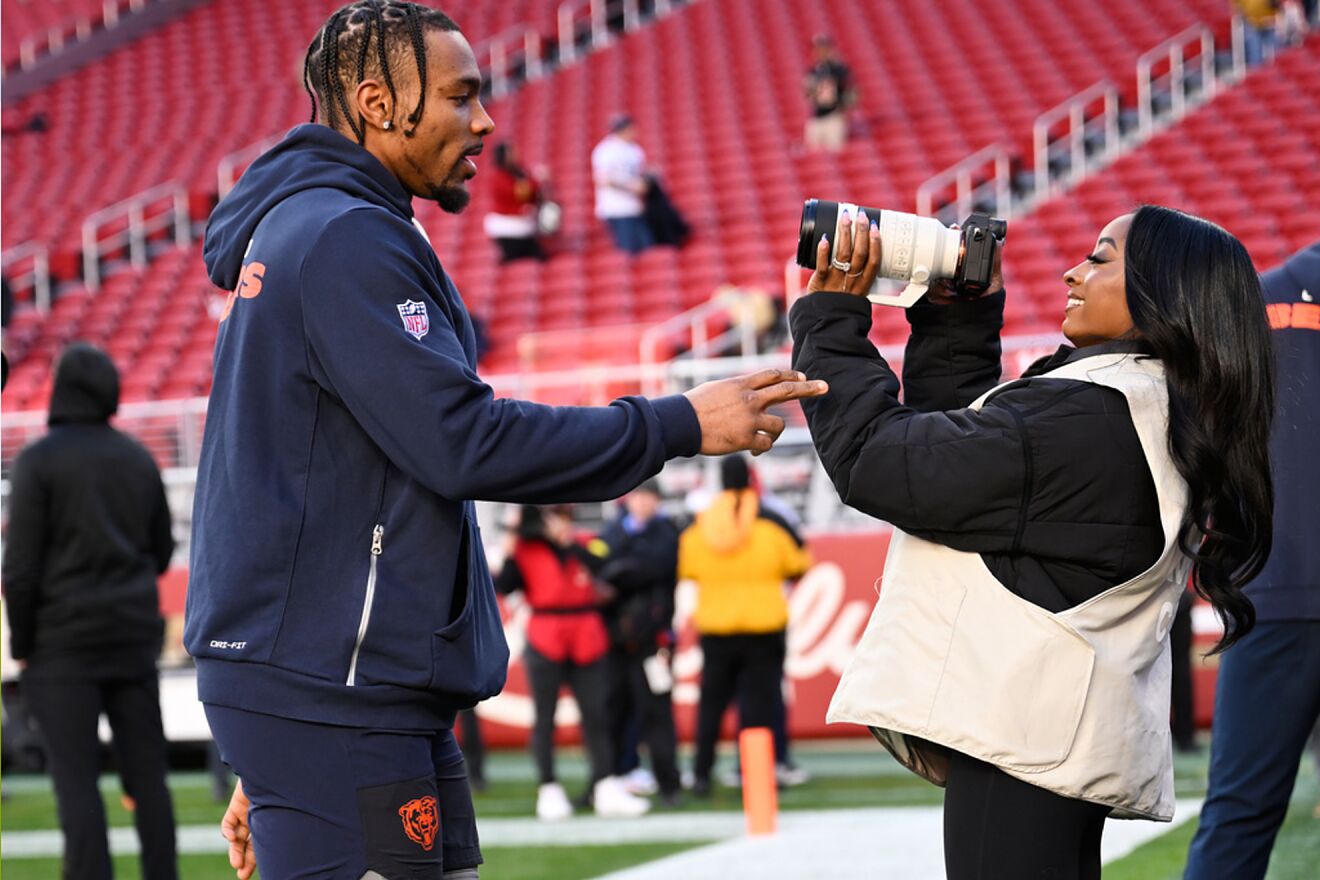 Simone Biles, right, takes photos of her husband, Chicago Bears...