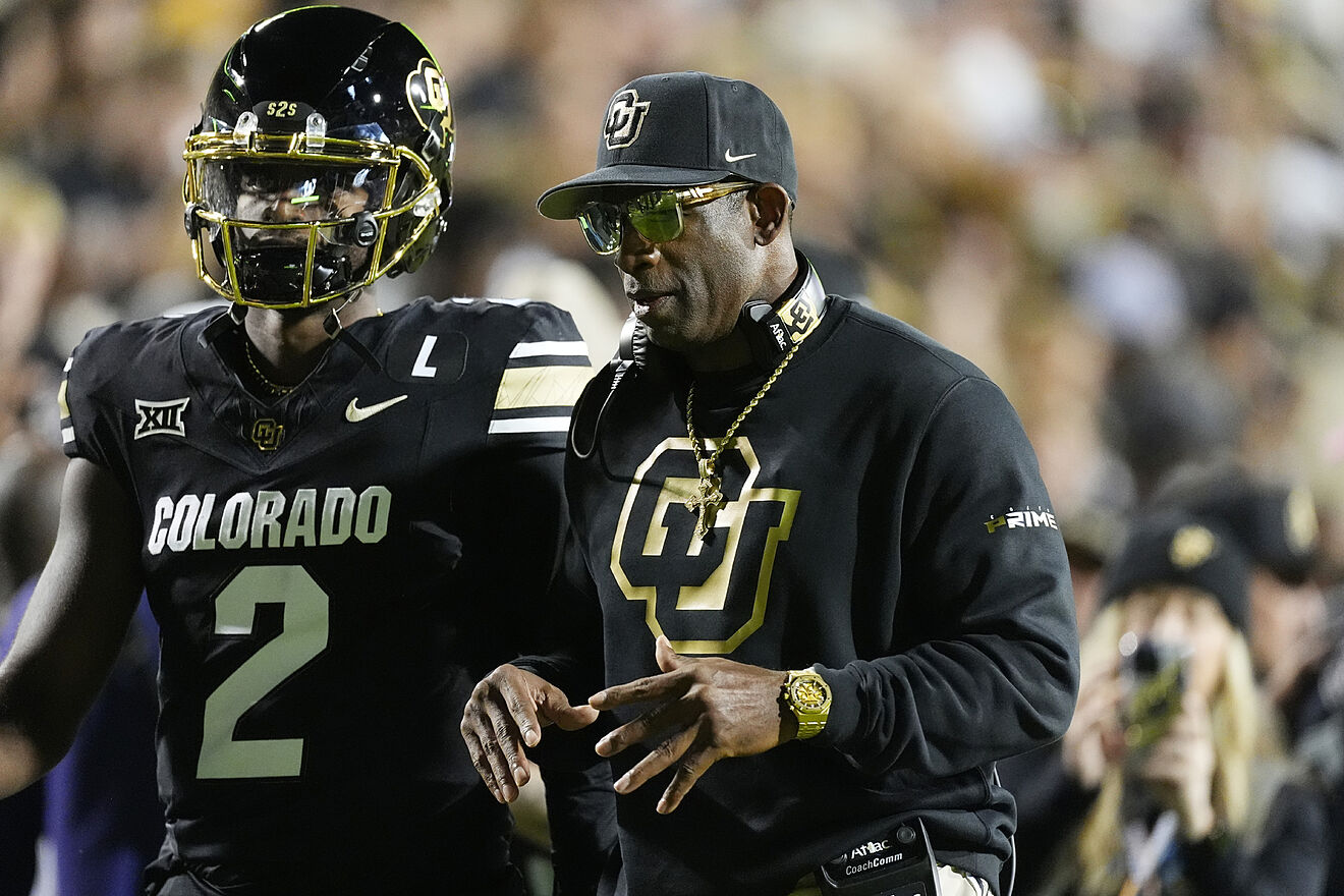 Colorado head coach Deion Sanders confers with his son, quarterback...