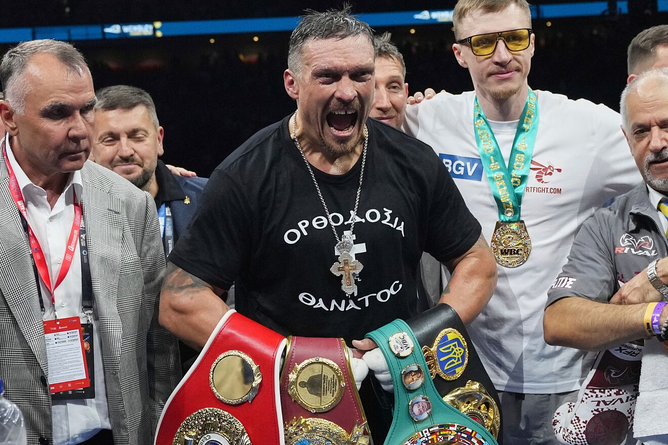 Oleksandr Usyk celebrates with his undisputed heavyweight titles after...